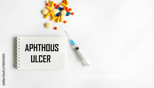 Medical term aphthous ulcer in a card on a white background with pills and an injection.