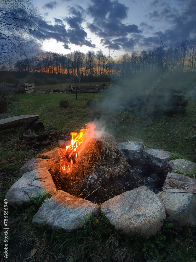 A smoking bonfire against the background of the setting sun A smoking bonfire against the background of the setting sun
