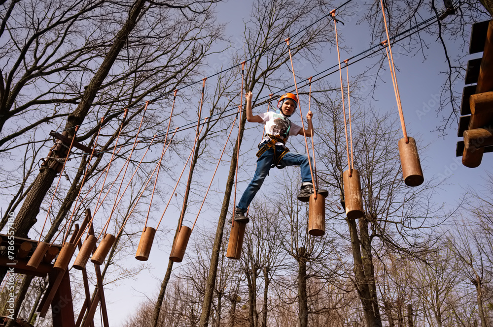 A boy in a helmet climbs a rope park in the spring A boy in a helmet climbs a rope park in the spring