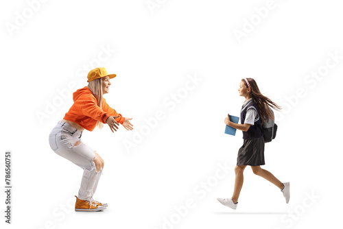 Full length profile shot of a schoolgirl running towards a young female with arms wide open