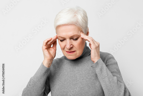 Senior woman with a headache pressing temples