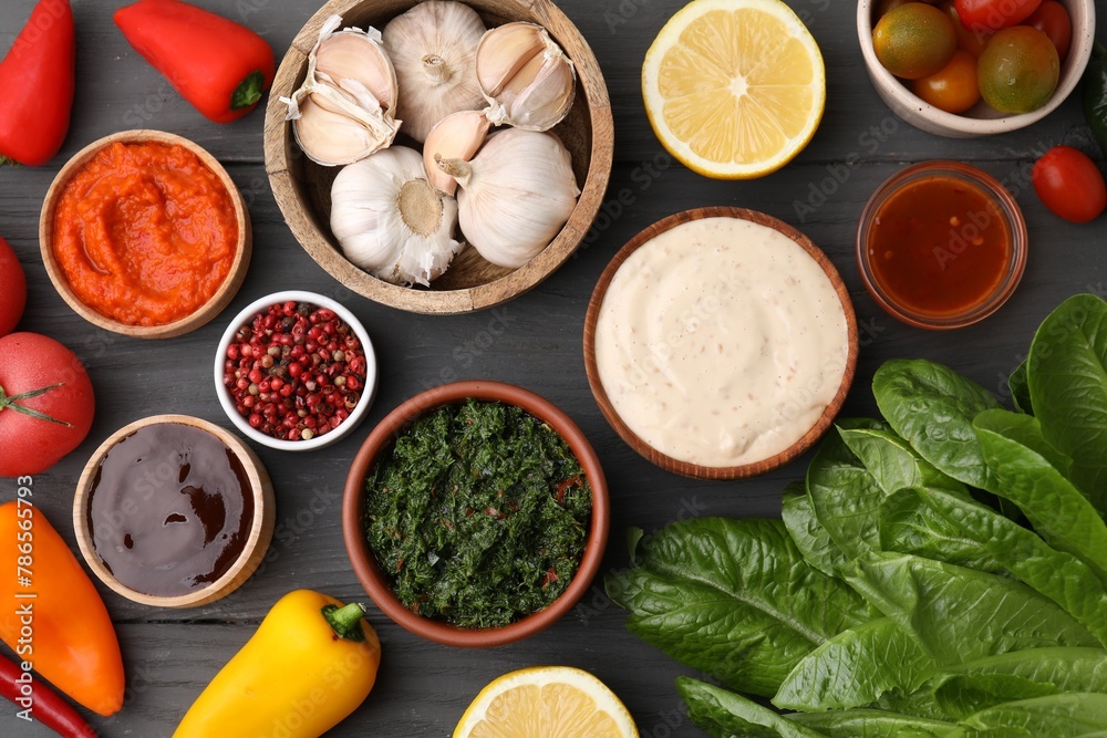 Different fresh marinades in bowls and ingredients on grey wooden table, flat lay