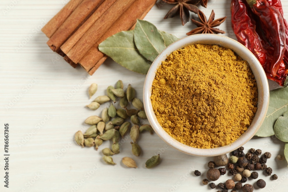 Curry powder in bowl and other spices on white wooden table, flat lay. Space for text Curry powder in bowl and other spices on white wooden table, flat lay. Space for text