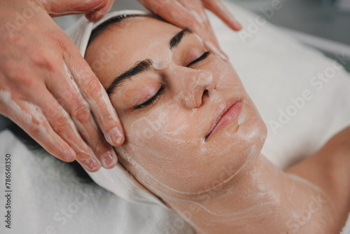 Qualified beautician cleansing caucasian man's face before beauty procedure at spa salon. Skincare cleansing spa relax concept