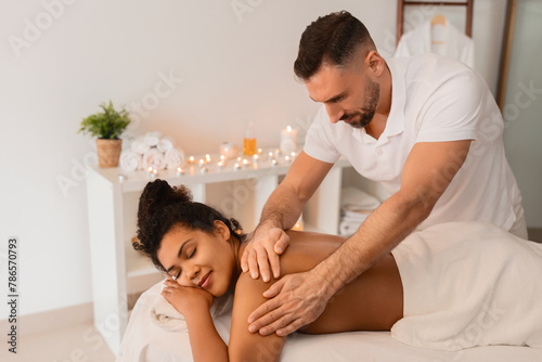 Massage therapist applying pressure to African American woman arm