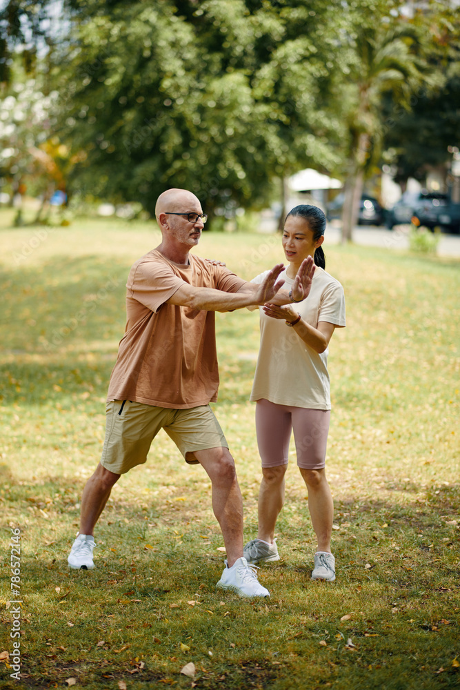 Fototapeta premium Mature man doing exercises outdoors with personal trainer