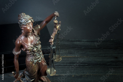 Themis and books on jurisprudence on a wooden background. Legal and law concept.