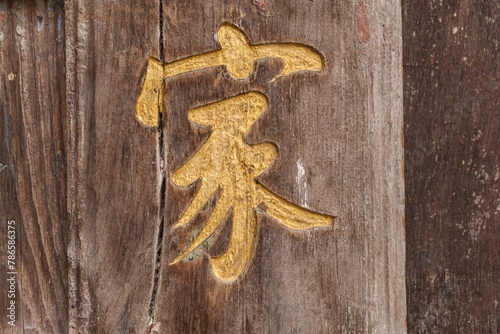 Close up of a gold colored carvings decoration on an old and weathered wooden door of a traditional house in the village of TuanShan, Yunnan province, China