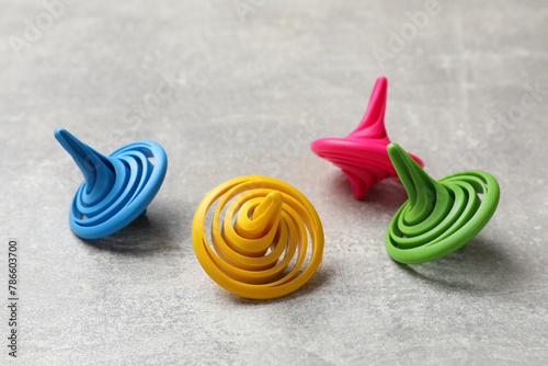 Bright spinning tops on grey textured background, closeup photo