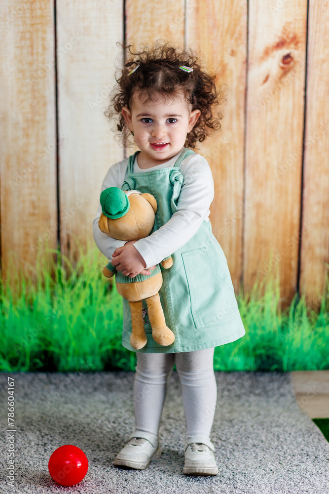 A joyful child clasping teddy bear on a wooden backdrop