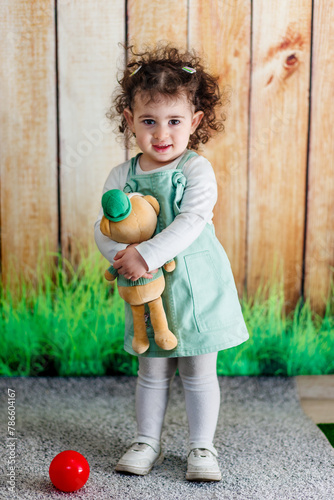 Obraz na płótnie A joyful child clasping teddy bear on a wooden backdrop w salonie