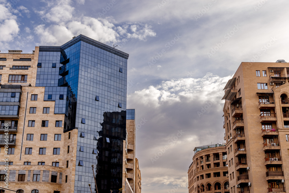 Modern skyscrapers towering over the city skyline against clouds.