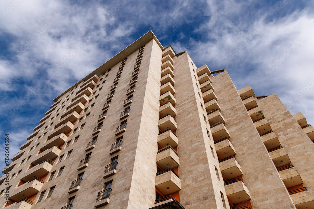 Tall modern apartment building with balconies reaching to the sky.