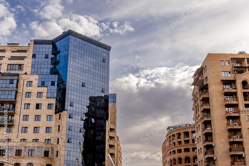 Obraz na płótnie Modern skyscrapers towering over the city skyline against clouds. w salonie