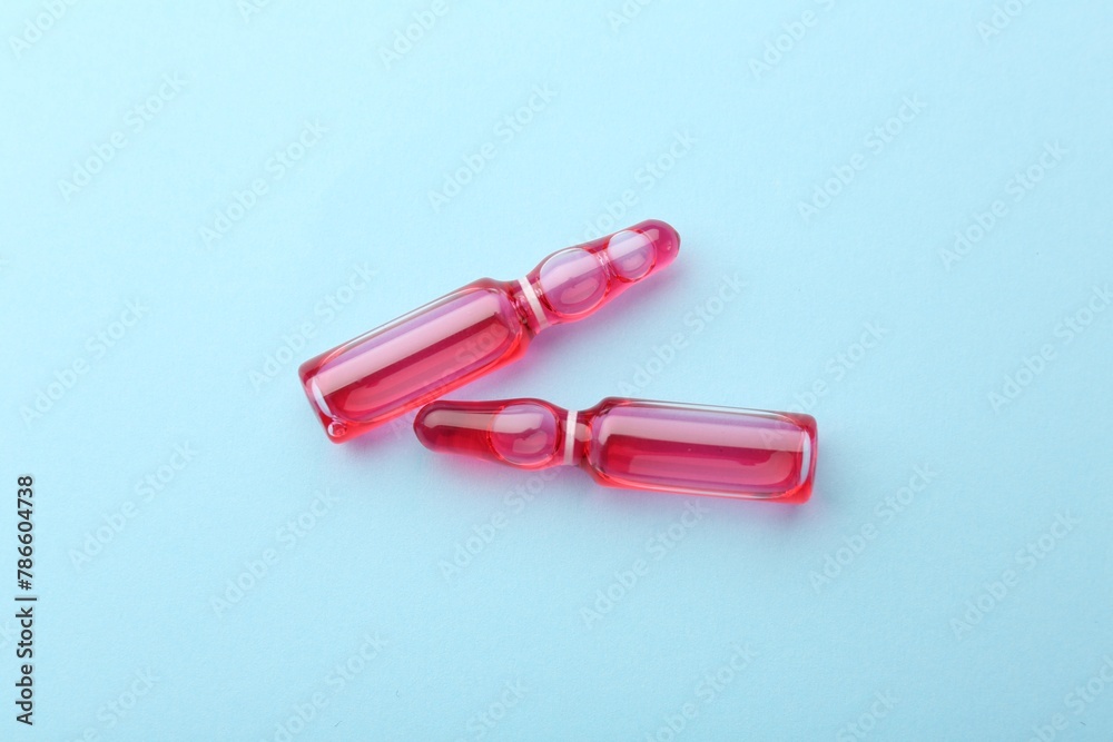 Glass ampoules with liquid on light blue background, top view Glass ampoules with liquid on light blue background, top view