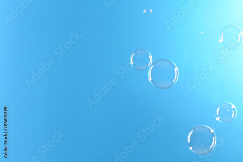 Beautiful transparent soap bubbles on light blue background  space for text