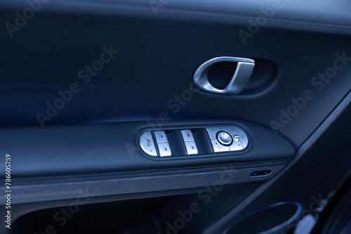 Car window controls. Door handle with power window control. Window control buttons in modern luxury electric car. Car leather interior details of door handle with windows controls and adjustments