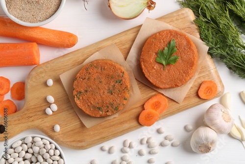 Uncooked carrot cutlets and ingredients on white wooden table, flat lay. Vegetarian product