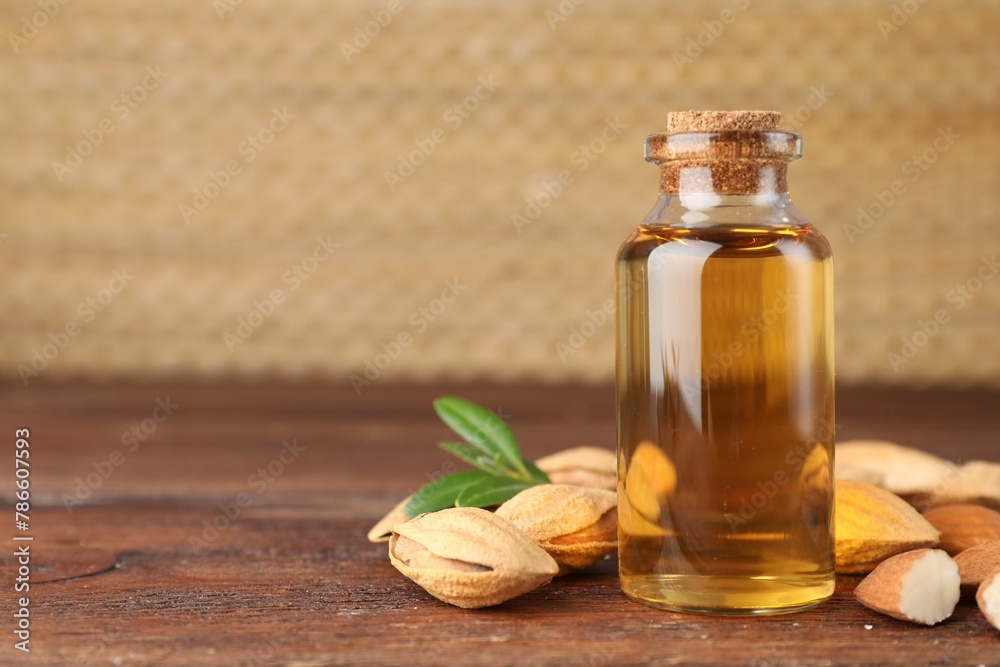 Almond oil in bottle, nuts and leaves on wooden table, closeup. Space for text Almond oil in bottle, nuts and leaves on wooden table, closeup. Space for text