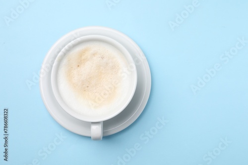 Aromatic coffee in cup on light blue background, top view. Space for text