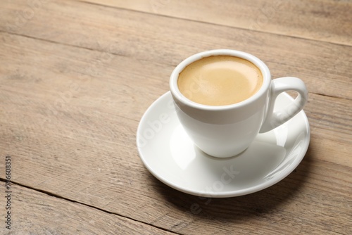 Aromatic coffee in cup on wooden table. Space for text