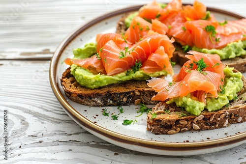 Toast bread with salted salmon and guacamole avocado in plate on wooden table