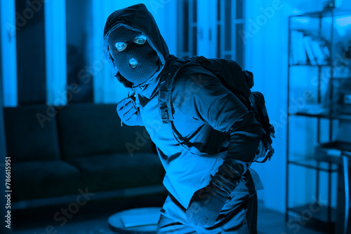 Burglar in mask sneaking inside a house