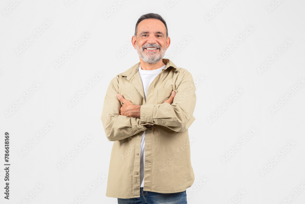 Senior man with arms crossed confidently on white background
