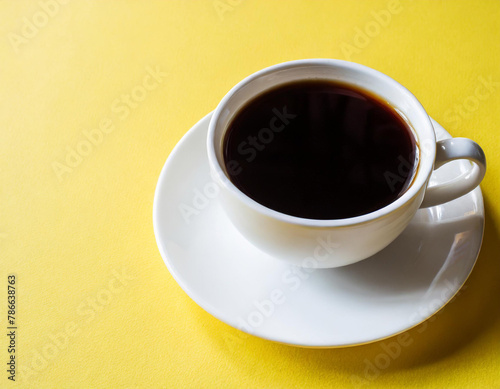 A cup of black coffee on a yellow background. © Nicolas