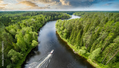 aerial view of a river in the middle of a forest with lots of green trees on both sides of the river and a boat in the middle of the water.