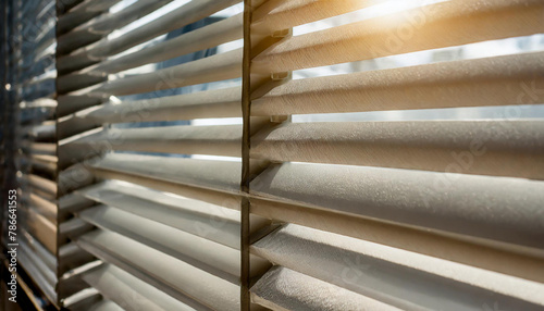 closeup of the blinds in an office window, with sunlight filtering through them creating diagonal stripes on their surface