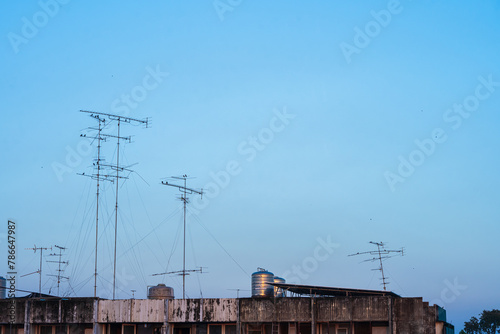 Old style Television (TV) Antenna and satellite on the roof with the house or building in provincial area in blue sky with cloud Background in Thailand,Analog TV receiver panels