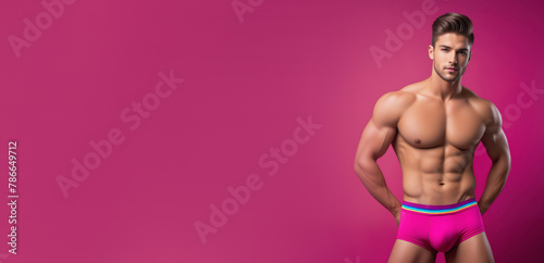 Confident muscular Caucasian man posing in bright pink underwear against a magenta background, concept for fitness modeling and LGBT Pride celebrations