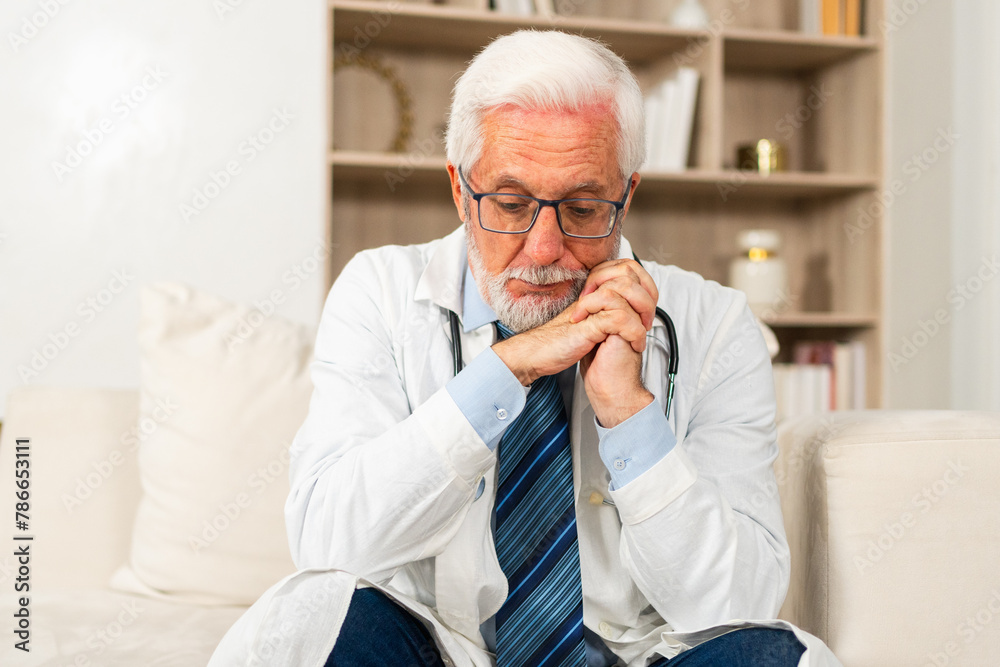 Sad tired mature senior male doctor in medical uniform in hospital or doctor office. Unhappy General Practitioner GP therapist professional healthcare expert in clinic. Healthcare concept Sad tired mature senior male doctor in medical uniform in hospital or doctor office. Unhappy General Practitioner GP therapist professional healthcare expert in clinic. Healthcare concept