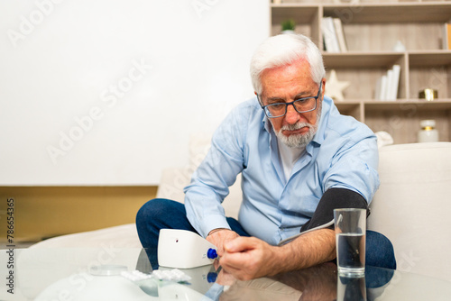 Hypertension problem in senior age. Old man measuring blood pressure with tonometer at home. Senior man have health problem making self checkup. Headache treatment of hypertension hypotension