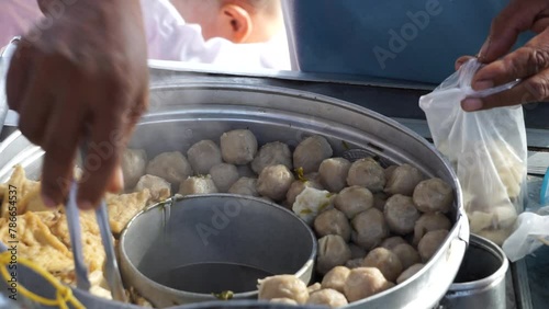 Bakso seller (meat ball seller) serves for customers in a stall cart. Bakso is one of indonesian street food photo