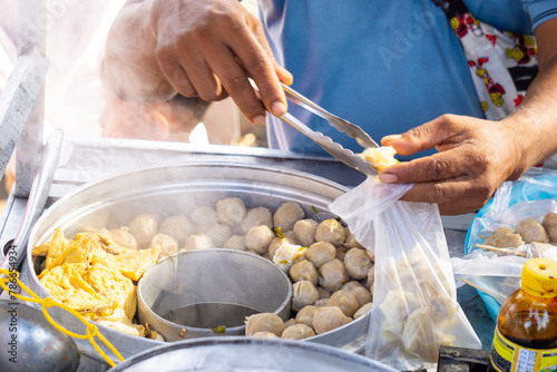 Bakso seller (meat ball seller) serves for customers in a stall cart. Bakso is one of indonesian street food photo