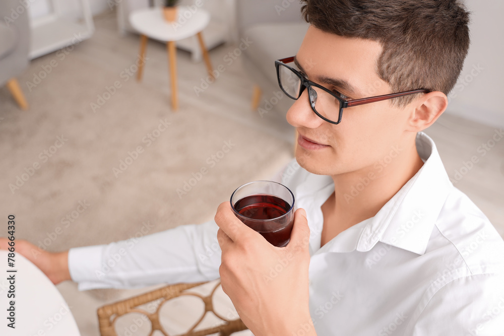 Young man with glass of juice in kitchen, closeup Young man with glass of juice in kitchen, closeup