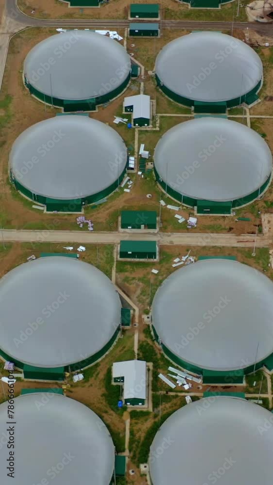 Modern biogas plant on field. Flying over the storage tanks for biomass production. Environmentally friendly biogas plant. Top view. Vertical video Modern biogas plant on field. Flying over the storage tanks for biomass production. Environmentally friendly biogas plant. Top view. Vertical video