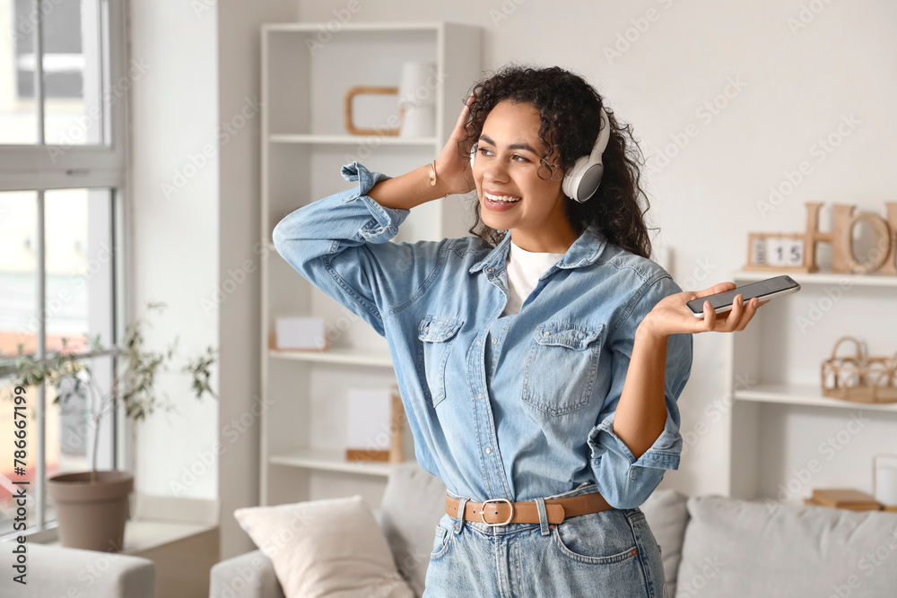 Young African-American woman in headphones with mobile phone listening to music at home