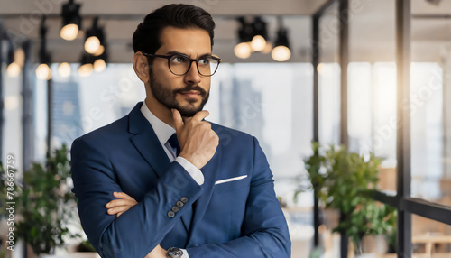 Serious confident mid aged business man, thoughtful doubtful company ceo executive wearing blue suit standing in office holding hand in chin looking at camera thinking, making decision, feeling doubt photo