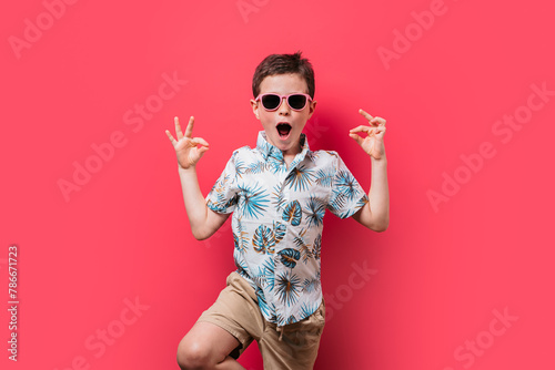 Excited boy in tropical shirt and sunglasses posing photo