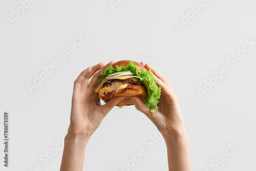 Female hands with tasty burger on white background photo