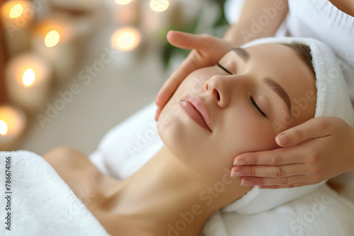 Peaceful woman receives a soothing lymphatic facial massage  surrounded by candles