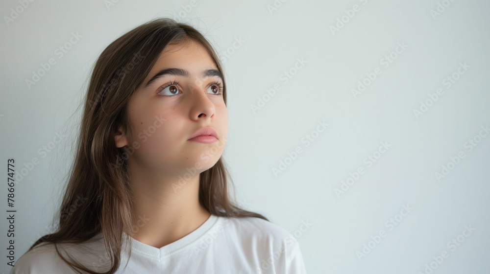A contemplative young girl looks aside to an empty background, embodying the mood of introspection and curiosity. A contemplative young girl looks aside to an empty background, embodying the mood of introspection and curiosity.