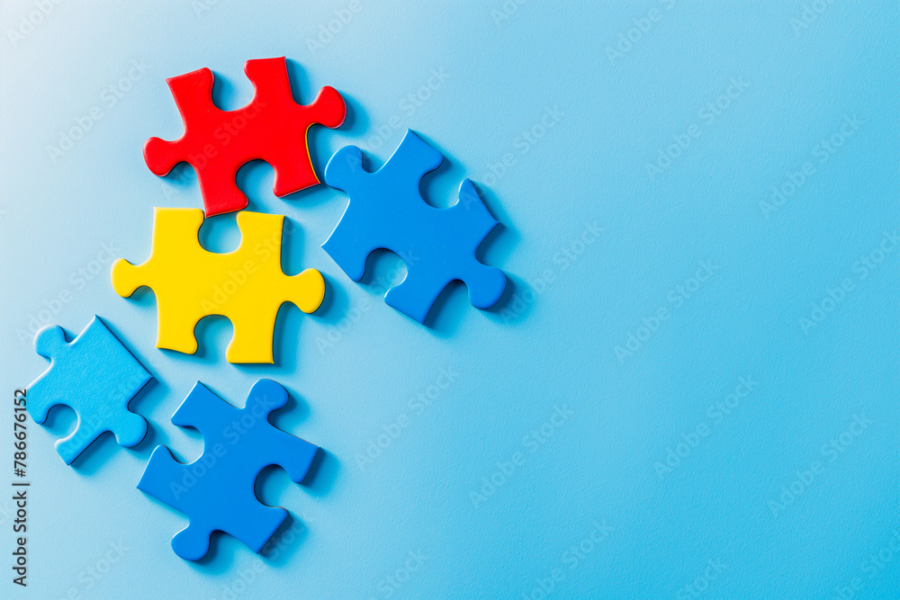 Blue, yellow, red pieces of puzzle on light blue background. World autism awareness day concept. Top view, copy space Blue, yellow, red pieces of puzzle on light blue background. World autism awareness day concept. Top view, copy space