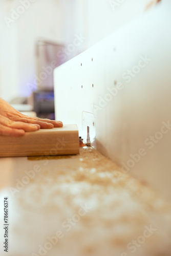 Man using edge jointer in carpenter studio for precision cutting of wood block  making wooden objects  close up shot. Focus on router planer used in woodworking by carpenter for smoothing out panels