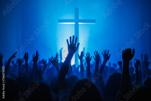 Christian worshipers raising hands up in the air in front of the cross photo