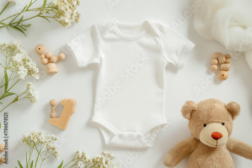 White cotton baby short sleeve bodysuit, teddy bear and natural wooden eco-friendly toys on pastel background. Infant onesie mockup. Blank gender neutral newborn bodysuit template mock up. Top view