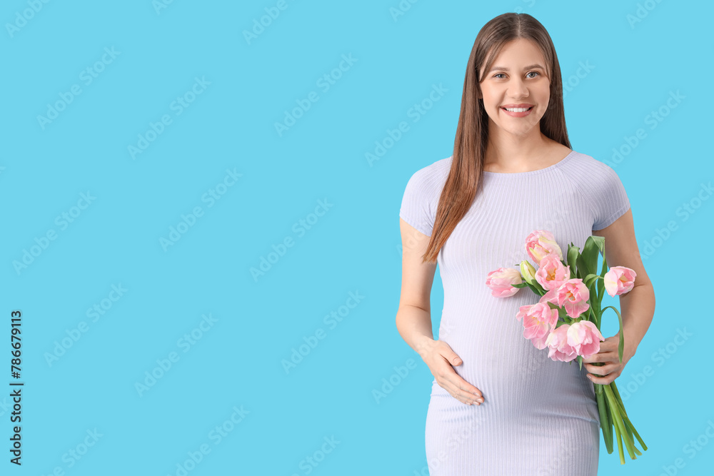 Young pregnant woman with tulips on blue background